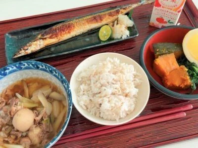 焼魚をメインにした和定食。中央に盛られたご飯、左上には焼き鮭、右側には煮物のような小鉢が写っている。バランスの取れた、健康的な食事の様子。