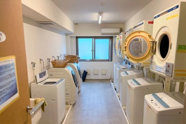 寮施設の共用スペースである洗濯室。縦型洗濯機が6台ドラム式洗濯機が2台乾燥機が4だいおいてある。