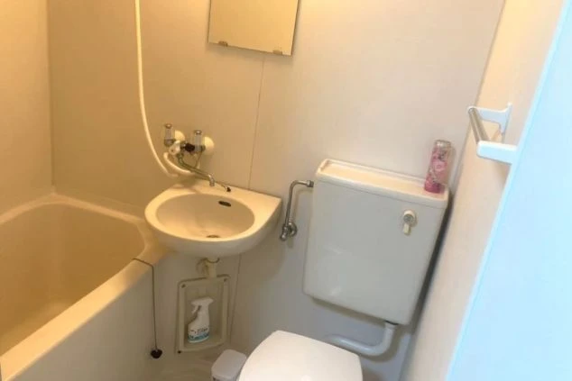 白を基調とした、清潔感のあるユニットバスの画像。便座、洗面台、バスタブがまとまって配置されている。リゾートバイトの寮の風呂場の画像。