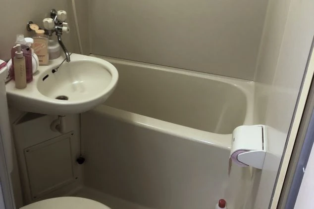 トイレと洗面ボウルが一体となったユニットバス形式の浴室。深めの浴槽が備わっており、蛇口の上にはシャンプーなどの日用品が置かれている。コンパクトで使い勝手の良さそうな設備。