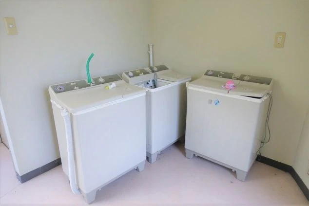 コンクリート風の床に設置された、3台の二槽式洗濯機。