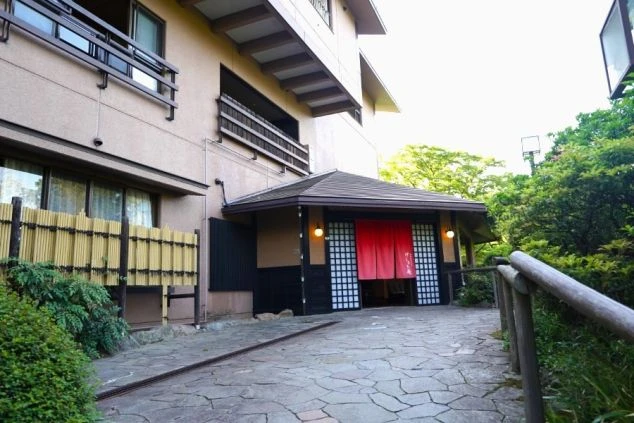 石段と赤い暖簾が印象的な旅館の玄関の写真。リゾートバイトの仕事を通して、このような風情ある空間で和のおもてなしを学べる魅力を伝えます。