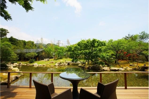旅館のテラスから眺める中庭の様子。大きな池と美しい木々が見える。