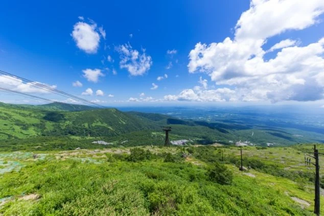 那須の山々を見下ろす広大な風景の画像。青い空と白い雲の下、緑豊かな山々と遠くの街並みが広がる。リゾートバイトの休日に訪れたい絶景。