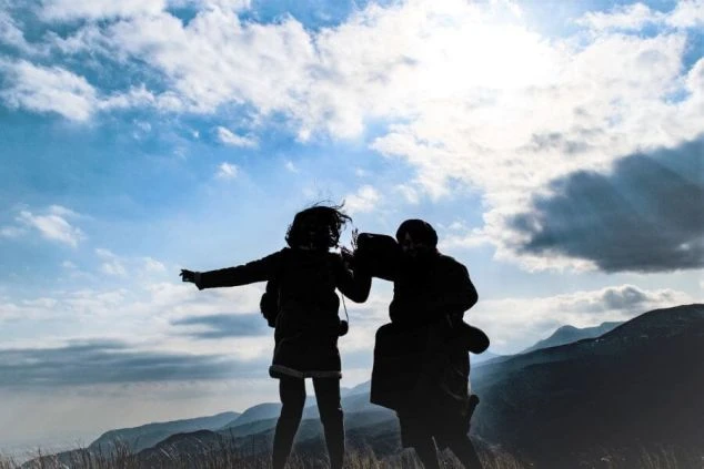 大自然の中で開放感！山頂でジャンプする二人のシルエット。リゾートバイトで心身ともにリフレッシュ！