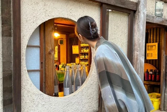 黒川温泉の風情ある街並みを散策するリゾートバイトスタッフの画像。休日に浴衣や羽織で温泉街の酒屋を巡る、住み込みバイトならではの贅沢なひととき。