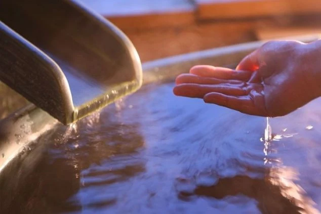 温泉の温度を確かめている画像。リゾートバイトは温泉が無料な求人多数