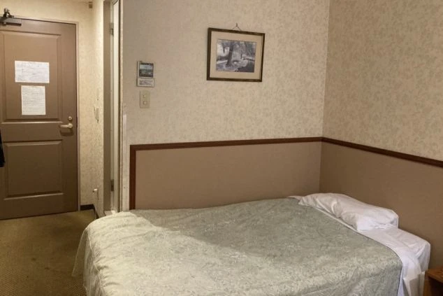 静岡県熱海のホテルでリゾートバイトをするスタッフが住む寮の画像。ホテルの客室に住める。ベッドが見える。