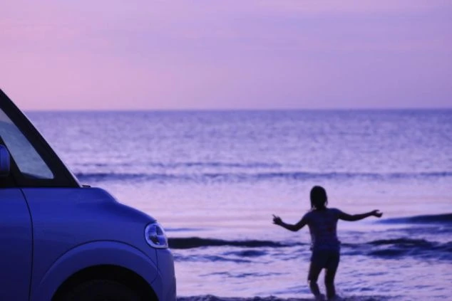 入水して遊ぶ人物と車の画像。夕焼けに染まる海が広がり、リゾートバイトの休日に海辺で過ごす開放感を表現している。