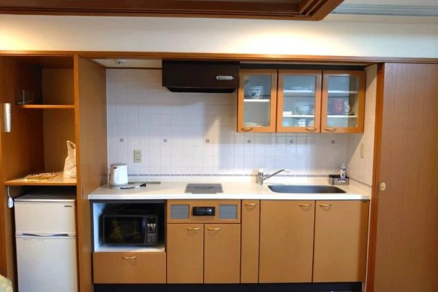 ワクトリの社員が出張で撮影した、リゾートバイトの客室寮のキッチンの画像。IHクッキングヒーター、シンク、冷蔵庫、電子レンジ、収納棚が一体となったシステムキッチンで、自炊に便利な設備が整っている。