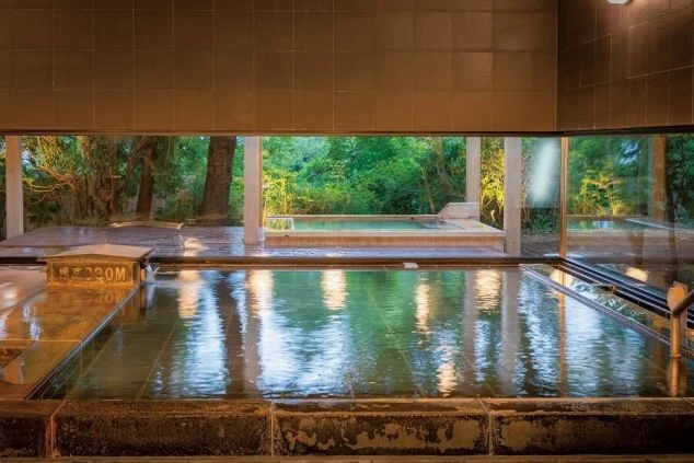 大きな窓から自然が見える、ホテルの温泉の画像。内湯と露天風呂が一体となっており、開放的な空間が広がっている。リゾートバイトの寮やホテルの福利厚生としても利用できる、温泉の画像。