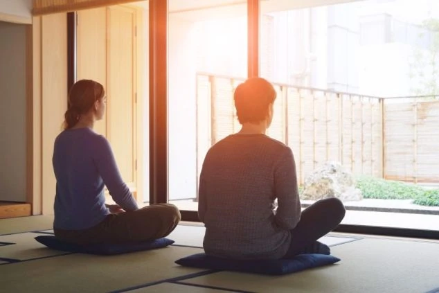 お寺の和室で、男女2人が座禅を組んでいる。縁側からは坪庭が見え、リゾートバイトの休日に、落ち着いた空間で静かな時間を過ごせることをアピール。