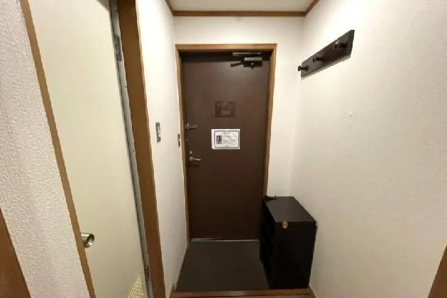 客室の入り口付近。茶色のドアの横には靴箱があり、壁にはハンガーラックが設置されている。