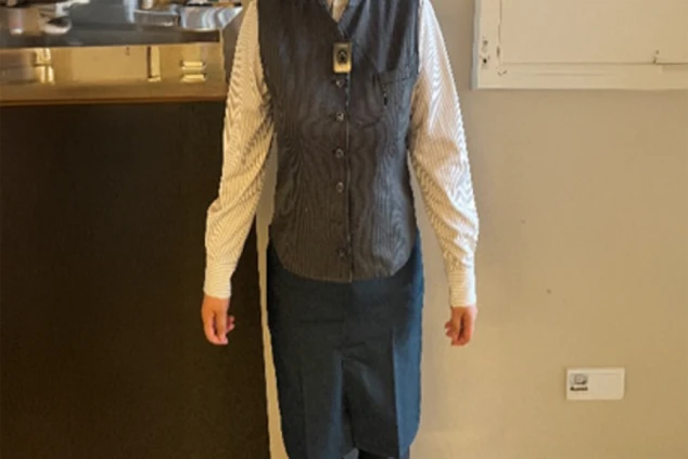 リゾートホテルのレストラン（女性）制服。ストライプシャツに黒のベストとエプロン。ホールスタッフのサービス業のリゾートバイト。