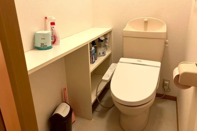 リゾートバイトの寮にあるトイレの画像。温水洗浄便座（ウォシュレット）完備で、棚には掃除用品などの収納スペースもある。