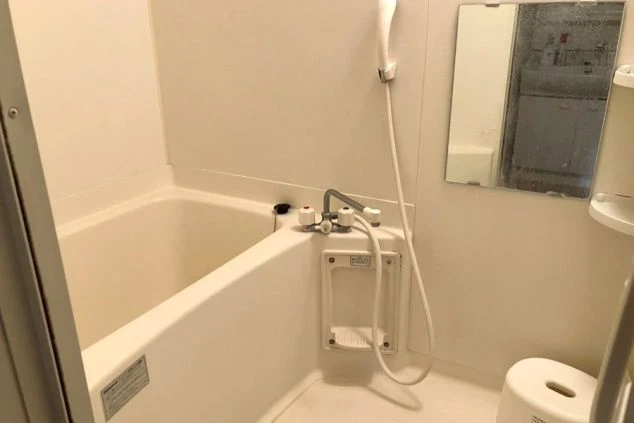 リゾートバイトの寮にある個室のバスルームの画像。鏡、シャワー、浴槽が揃ったユニットバス。