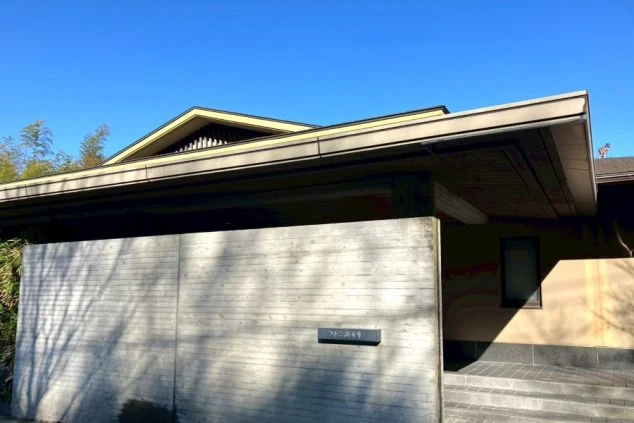 空に映える、モダンで落ち着いた佇まいの高級旅館の外観画像。