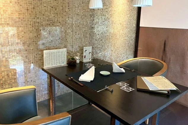 モダンなタイル壁と温かみのある照明が印象的な、個室感のあるレストラン内観画像。