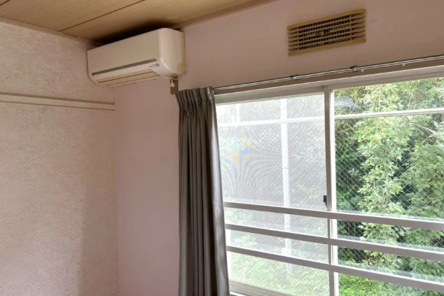 ワクトリの社員が出張で撮影した、リゾートバイトの寮の部屋の画像。窓から緑豊かな景色が見え、エアコンと換気口が設置されている。快適な室温で過ごせる寮の居住環境を示す。