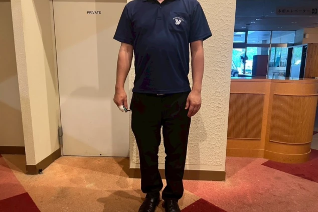 紺色のポロシャツと黒いパンツを着用した男性スタッフの姿。