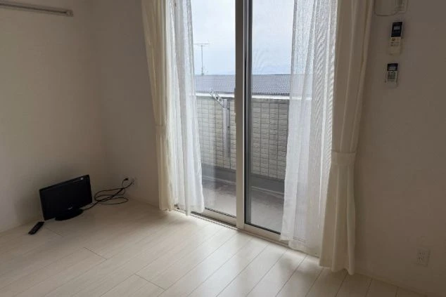 採光のよい個室(居室)で、白いカーテンとミニテレビが置かれている。