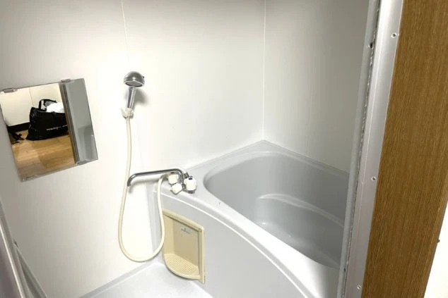 寮の個室内に完備されたバスルーム。鏡付きのシャワーと浴槽があり、仕事の疲れをゆっくり癒やせる清潔な水回り環境。