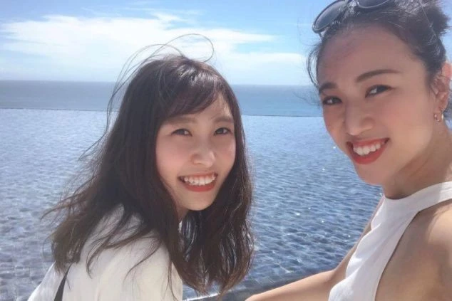 インフィニティプールのそばで笑顔の女性2人の画像。リゾートバイトで友達同士の応募、または新しい仲間と出会うイメージ。