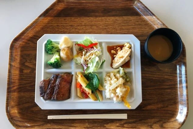 リゾートバイト求人のまかない画像。木製トレイに乗った、おかずの種類が豊富な定食スタイルの食事。