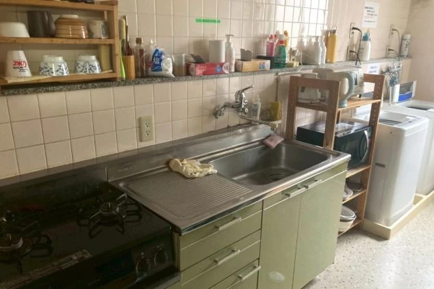 自炊も洗濯もできるリゾートバイト寮の共同スペース。ガスコンロ、シンク、洗濯機が並んだ生活機能が充実した設備。