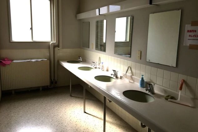 複数の蛇口と鏡を備えた、明るくきれいな共同洗面所。混雑時にも利用しやすいよう洗面台が並んだ寮。