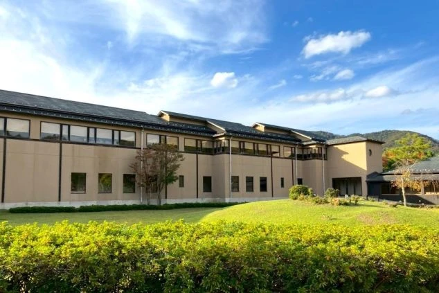 城崎温泉の柳並木を背景に、マスクをつけた二人の女性が記念撮影をしている。夜の温泉街の風情ある雰囲気を楽しんでいる様子。