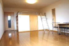 寮の居室。光沢のあるフローリングで、天井近くにロフトまたは収納スペースがあり、梯子(はしご)がかけられている。