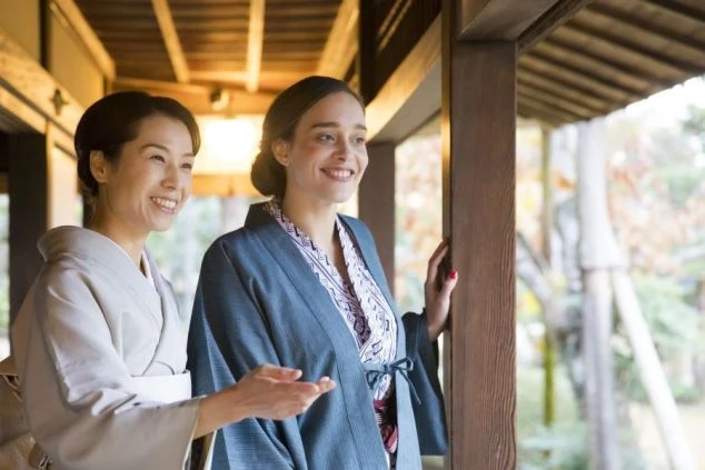 海外のお客様に庭を案内している女将のイメージ画像。