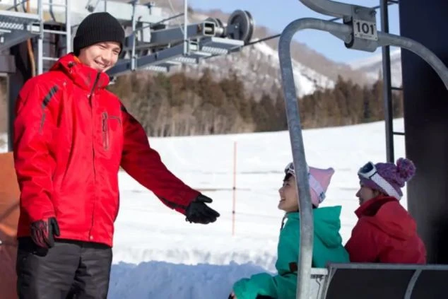 リゾートバイトで、スキー場のリフト係として働く男性。お客様を笑顔で迎える、冬のリゾート地での接客の仕事。