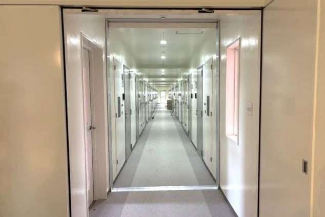 リゾートバイトの寮の廊下の画像。両側に部屋のドアが並び、奥まで続く長い廊下が印象的。共同生活の場としての寮の内部を示す。