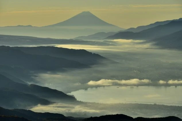早朝の長野県諏訪湖を覆う雲海と遠景に浮かぶ富士山。