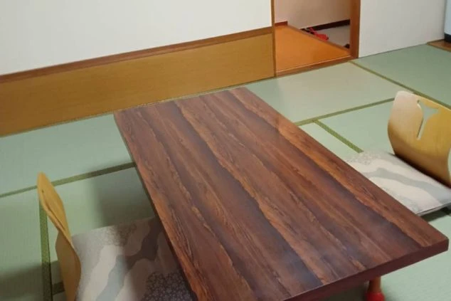 寮の和室。木目調のローテーブルと座椅子、畳の床が映る。