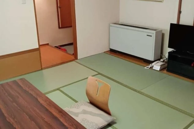 寮の和室。木目調のローテーブルと座椅子、畳の床が映る。