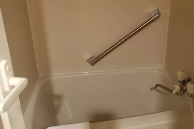 寮のお風呂。手すり付きの白い浴槽が映る清潔な空間。