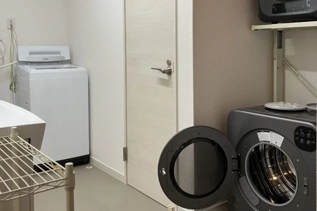 リゾートバイトの寮の洗濯スペースの画像。手前にはドラム式洗濯機、奥には縦型洗濯機が設置されており、複数の人が同時に利用できる。リゾートバイトの寮の共用スペースの画像。