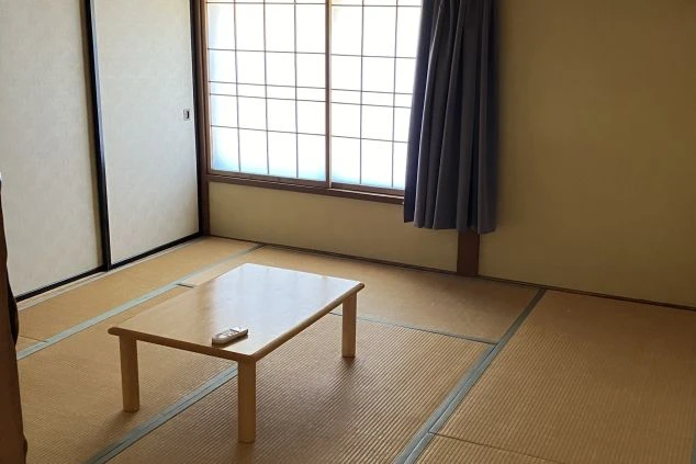 リゾートバイトの寮の部屋の画像。和風の畳の部屋で、窓の外には明かりが見える。リゾートバイトの寮の部屋の画像。