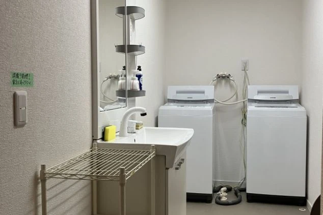 リゾートバイトの寮の洗面所を撮影した画像。シンクの横には2台の洗濯機が設置されており、壁には鏡が備え付けられている。リゾートバイトの寮の共用スペースの画像。