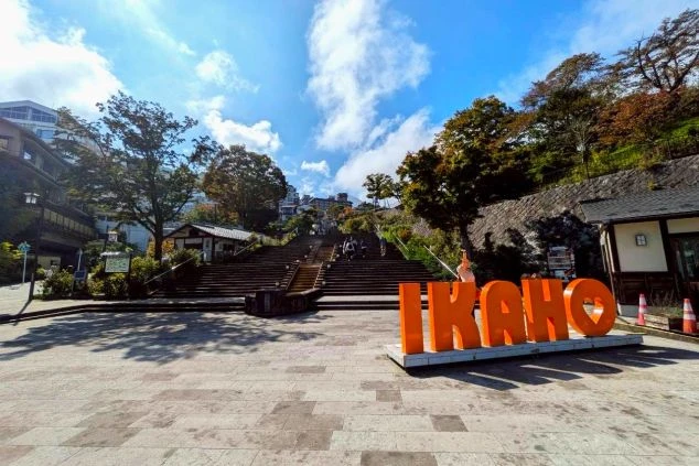 青空の下、広場にある大きな「IKAHO」のオブジェと、その先に続く伊香保温泉の石段街。リゾートバイトの休日に観光を楽しめます。
