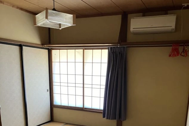 リゾートバイトの寮の部屋の中を撮影した画像。エアコンと窓が写っており、ハンガーをかけるバーが備え付けられている。リゾートバイトの寮の部屋の画像。