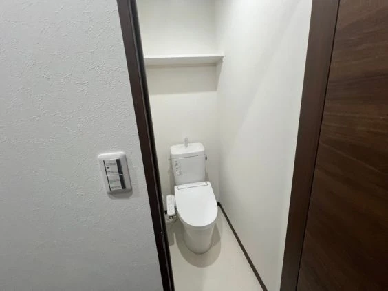 寮のトイレ。温水洗浄便座と棚が映る清潔な空間。
