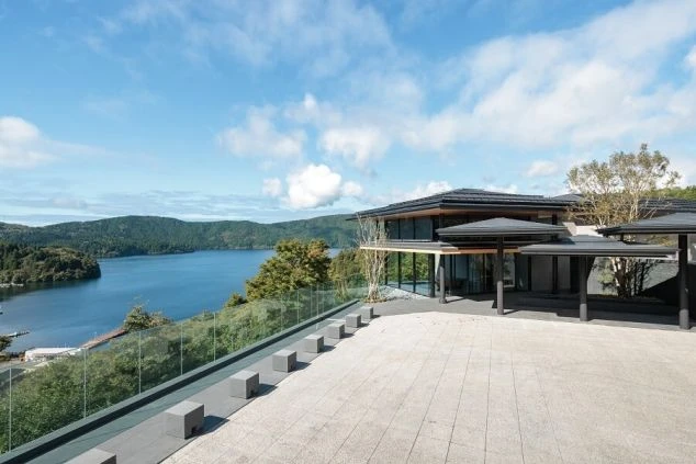 湖畔に建つモダンなホテル。大きなテラスから湖と山々が広がる絶景が映る職場のイメージ画像。