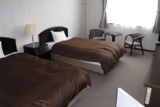 リゾートバイトの寮の洋室。ベッドが2台置かれた、広々としたホテル客室のような部屋です。窓際のテーブルセットで、仲間とゆっくり過ごせます。