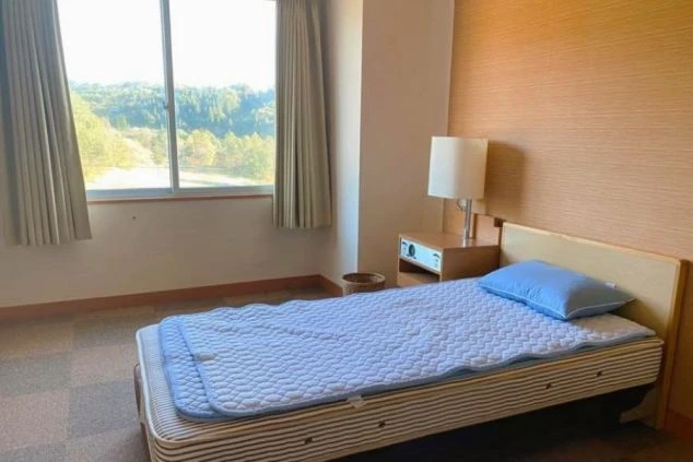 リゾートバイトの寮にある個室。窓から自然が見える明るい部屋で、ベッドや照明が備え付けられ、快適な一人暮らしが可能。