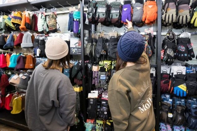 スキー場にあるショップで、カラフルなニット帽やグローブを選ぶ女性二人。リゾートバイトの給料で、お気に入りのギアを新調するのも楽しみの一つです。