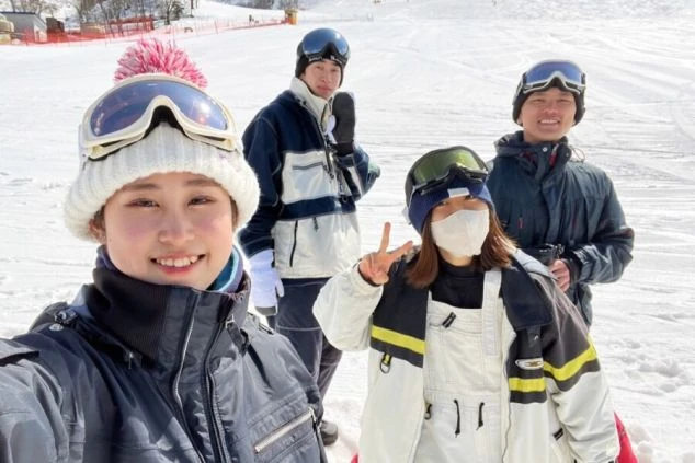 ワクトリでリゾートバイトをしたスタッフが撮影した、スキー場で楽しそうにポーズをとる4人の若者。皆、防寒着とゴーグルを身につけている。